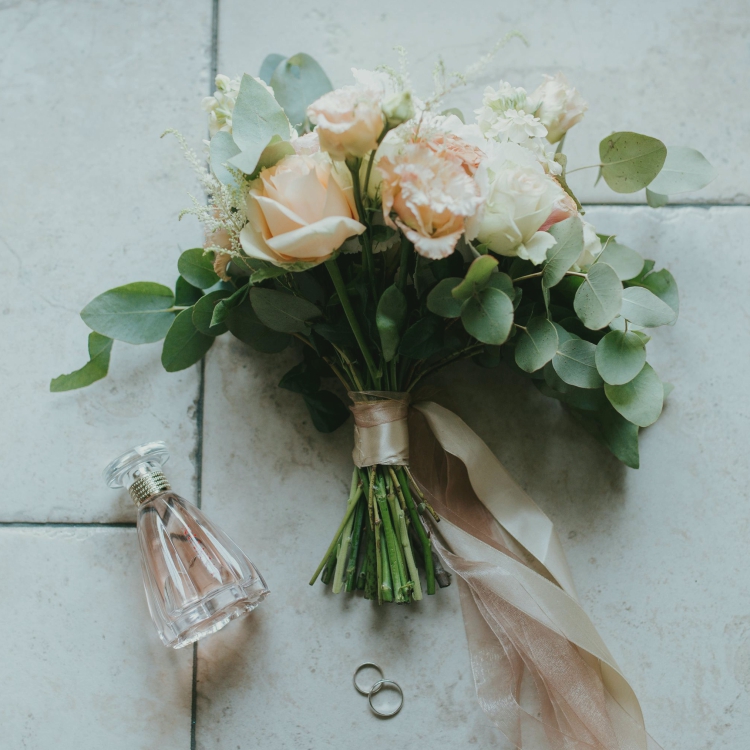 ramo de boda en el piso con anillos y perfume