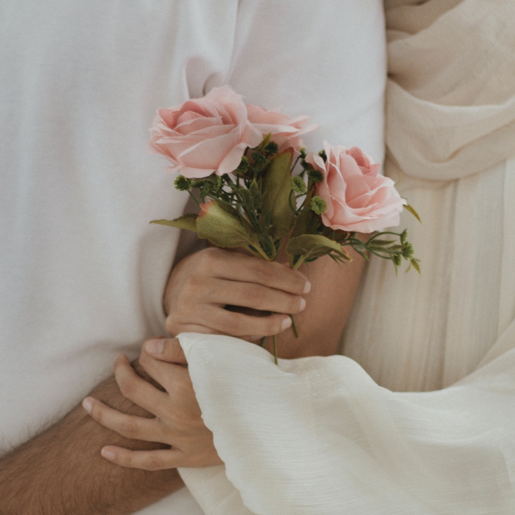 manos entrelazadas con rosas rosas