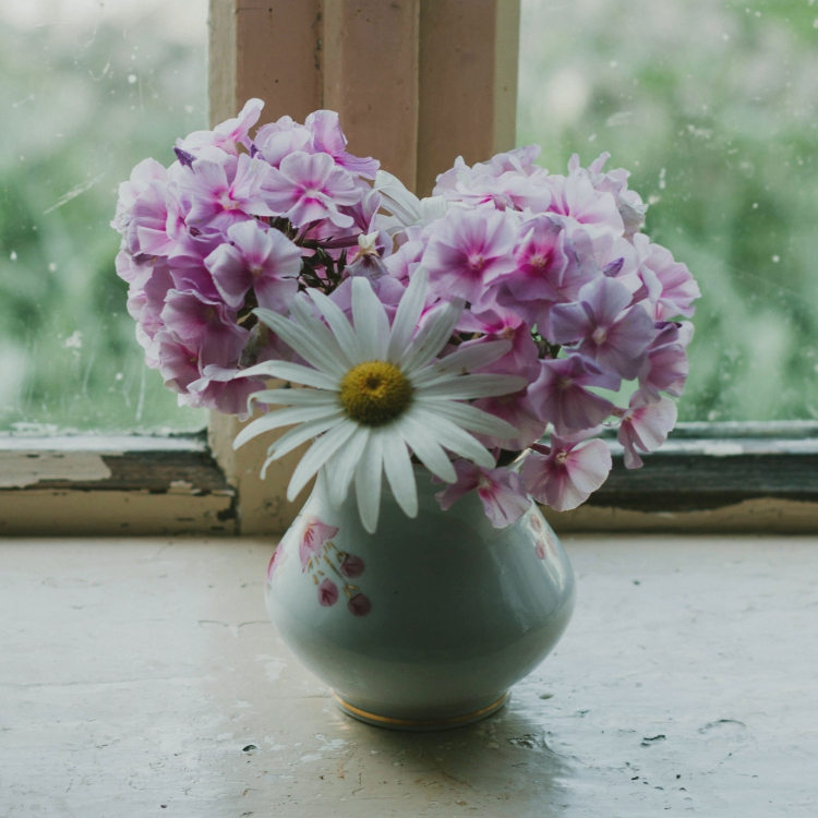florero vintage con flores delante de ventana
